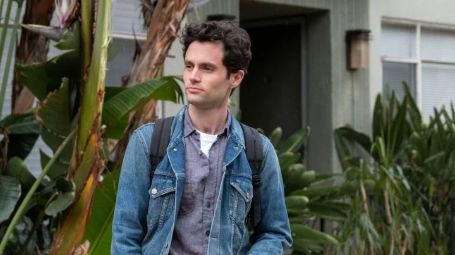 joe standing on the side walk in a blue jeans jacket carrying a back pank 